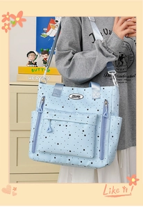 Dettaglio della borsa tote in tela azzurra con motivo a stelle e tasca anteriore con spalline