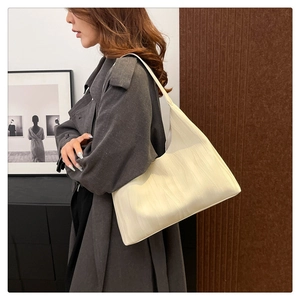 Detail of cream white hobo bag with ripple embossed texture worn on model's shoulder