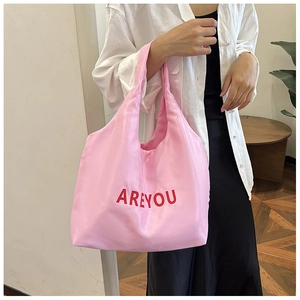 Détail d'un sac cabas en satin rose avec lettrage rouge AREYOU et doubles poignées