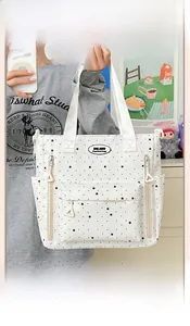 Dettaglio di una borsa tote in tela bianca con stelle nere e tasche multiple con cerniera