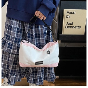 Detail of a color-block canvas crossbody bag with pink accents and black shoulder strap