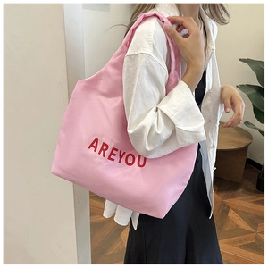 Gros plan détaillé du cabas rose avec impression de lettres AREYOU rouges sur le tissu