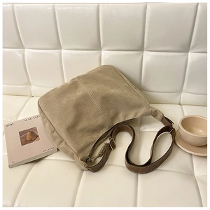 Détail du sac hobo en toile kaki avec bandoulière réglable sur un canapé douillet