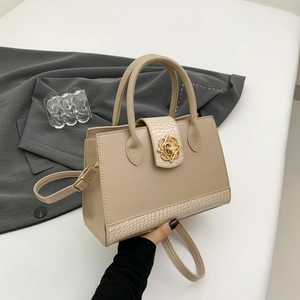 Sac fourre-tout beige rétro avec texture crocodile et boucle fleur dorée présenté à la main