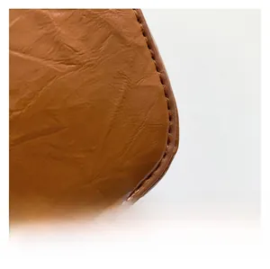 Close-up of caramel leather texture with vintage wrinkles and neat manual stitching
