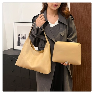 Detail of minimalist beige tote bag and small pouch set shown with a grey coat