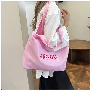Détail macro d'un sac cabas en nylon rose avec lettrage AREYOU rouge et finition brillante