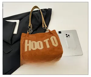 Détail d'un grand sac cabas en daim marron avec lettrage HOOTO et bandoulière chaînée