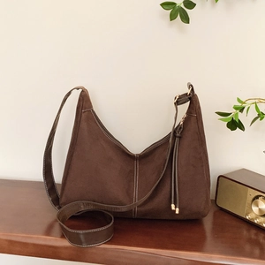 Sac hobo vintage en daim marron foncé avec surpiqûres contrastées sur table