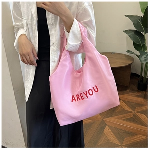 Détail d'un sac cabas rose en toile avec texte rouge AREYOU dans un intérieur moderne