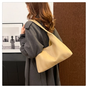 Detail view of beige PU leather tote bag worn as a shoulder bag on a model