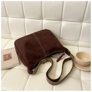 Détail du sac cabas vintage marron avec surpiqûres et bandoulière réglable sur le canapé