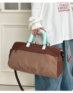 Detail of checkered travel bag showing durable handles and adjustable shoulder strap