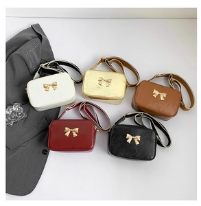 Flat lay of small square bow bags in white, gold, brown, red, and black colors