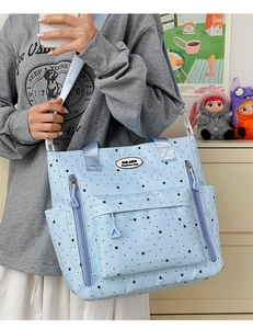 Borsa a tracolla celeste con stelle nere indossata da una modella in una stanza calda