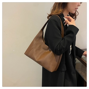 Detail of soft brown tote bag with wood grain texture shown on shoulder for daily office use