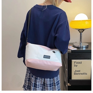 Detail of canvas crossbody bag showing pink and white patchwork and adjustable strap