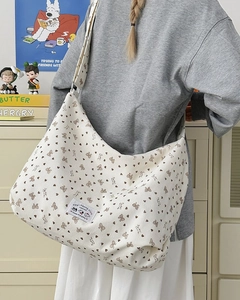 Detail of white corduroy tote bag with brown bow patterns and adjustable shoulder strap