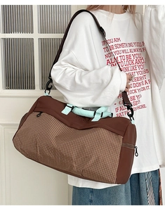 Detail view of the large capacity plaid travel bag with mint green handles and long strap