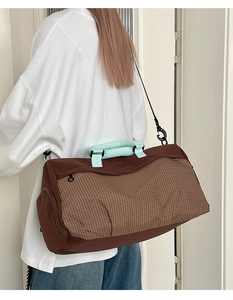 Detailed back view of a large travel bag with brown plaid panels and blue handles