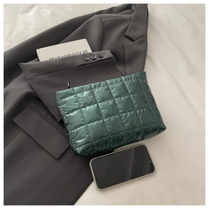 Close-up of dark green quilted nylon cosmetic bag with soft texture and metallic zipper