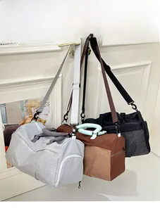 Three large fitness travel bags in light grey, brown, and black hanging from a door
