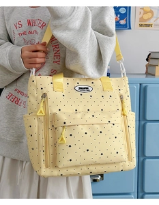 Dettaglio della borsa tote in tela gialla con motivo a stelle, tasche con zip e tracolla