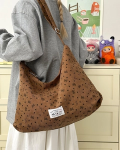 Detailed view of brown corduroy hobo bag with bow patterns and adjustable strap