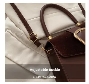 Detail showing the adjustable golden buckle and mixed leather texture on the brown handbag