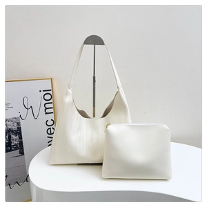 Detail view of the white textured tote bag set with matching small zipper pouch on art display