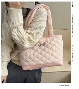 Close-up of a light pink quilted shoulder bag featuring a metallic bow and diamond stitching