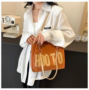 Détail du cabas en daim orange avec patch HOOTO et fines lanières en cuir brun