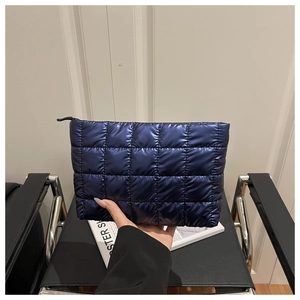 Close-up of a metallic blue quilted cosmetic pouch with a puffer texture and zipper