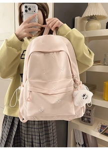 Detail of light pink backpack with flower embroidery and a plush puppy keychain