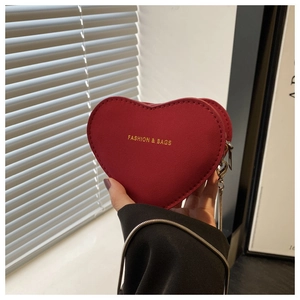 Détail du mini sac rouge en forme de cœur avec texte doré et bandoulière en chaîne
