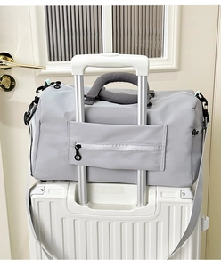 Close-up of the grey travel bag's back sleeve securely fitted onto a suitcase handle