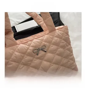 Close-up of pink quilted nylon tote bag featuring detailed diamond stitching and bow charm