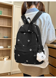 Detail of black backpack with small white floral patterns and soft plush cloud charm