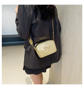 Close-up of metallic gold crossbody bag with 3D bow detail and wrinkled texture finish