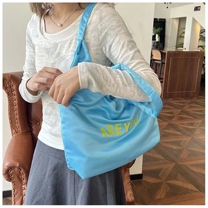 Détail du grand sac cabas en satin bleu avec inscription AREYOU jaune à l'épaule