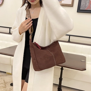 Grand sac hobo marron vintage avec large bandoulière porté par un mannequin dans un salon
