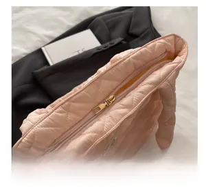 Detail of the smooth golden metal zipper closure on the pink quilted tote bag