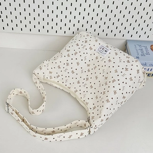Detail of off-white corduroy shoulder bag with brown bow prints and metal buckle