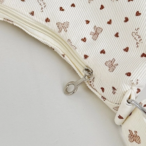 Detail of corduroy texture with brown heart patterns and silver zipper puller