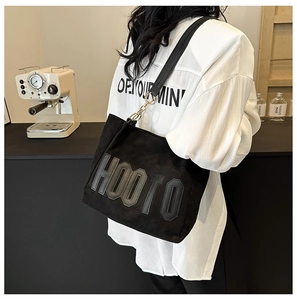 Détail du cabas en daim noir avec logo HOOTO, bandoulière en cuir et anneaux dorés