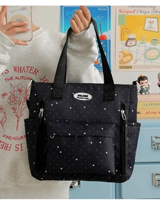 Dettaglio borsa nera stellata con tasche multiple con cerniera e tracolle regolabili