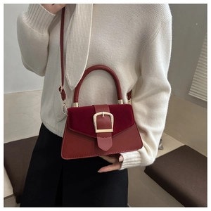 Detail of burgundy crossbody bag featuring a matte suede and smooth leather patchwork