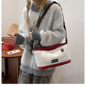 Detail of red and white canvas messenger bag with adjustable strap and casual utility style