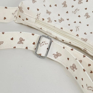 Detail of white corduroy bag with brown heart patterns and silver metal buckle