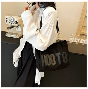Détail du sac cabas noir avec lettrage HOOTO et bandoulière en chaîne dorée